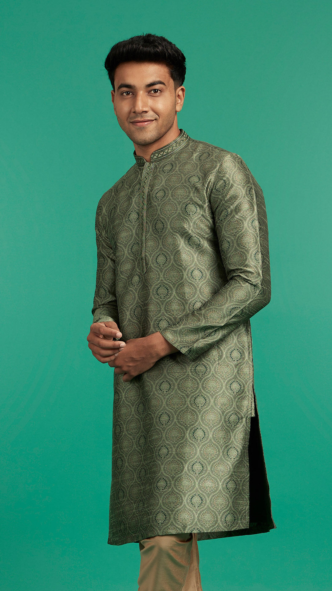Man wearing a traditional green jacquard kurta with beige trousers, posing stylishly against a solid green background